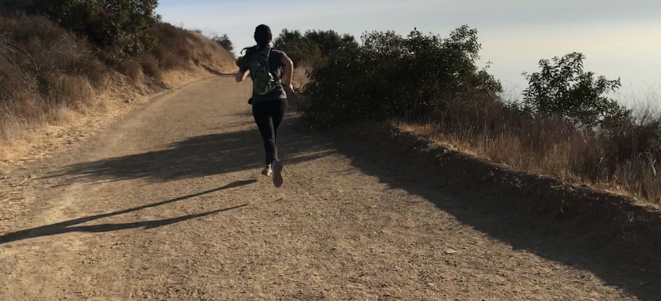 Lindsay Haddock running uphill on an outdoor trail.